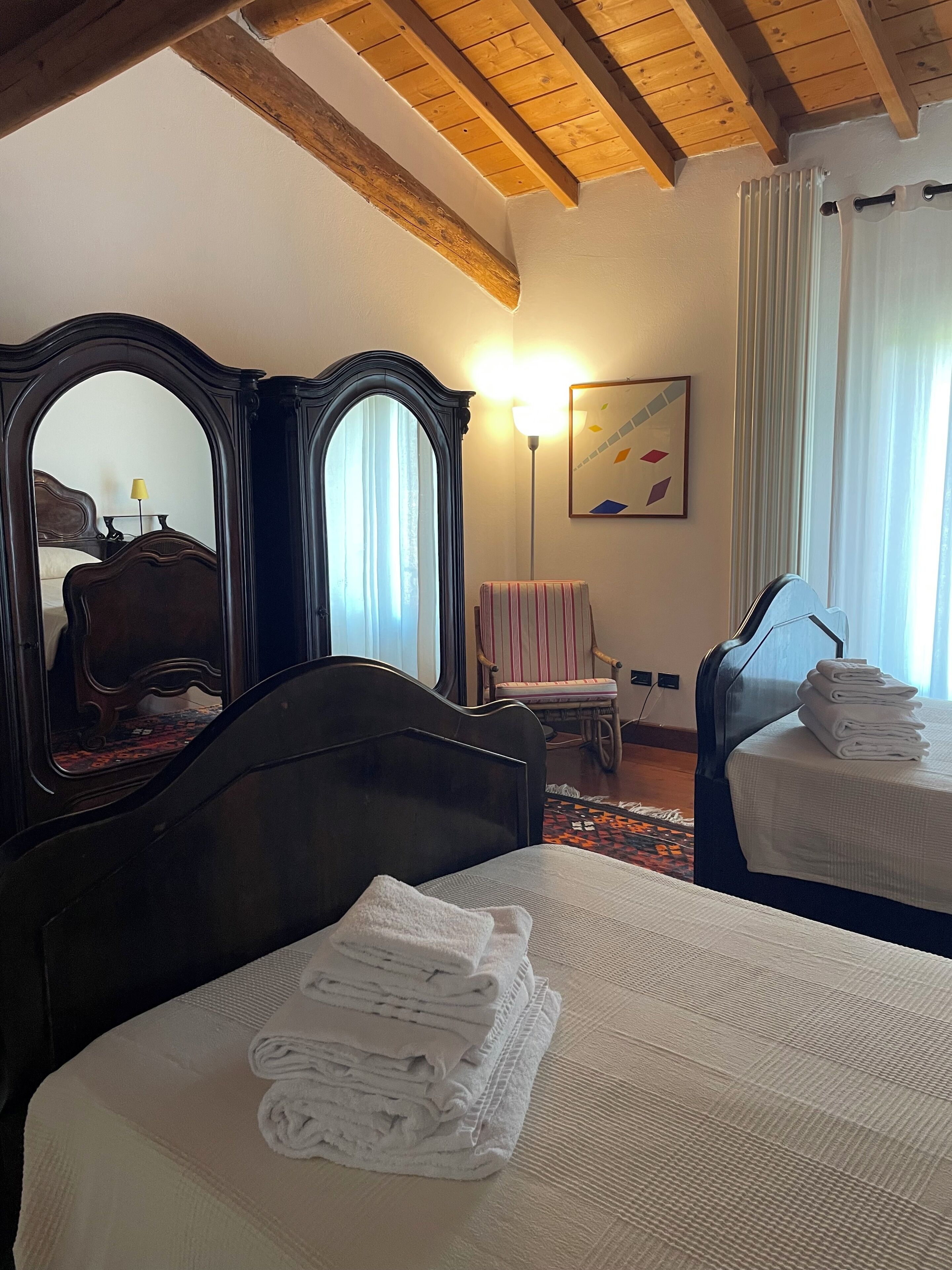 Un dormitorio con una cama grande, cabecera de madera, espejo, una silla y una mesita de noche.
