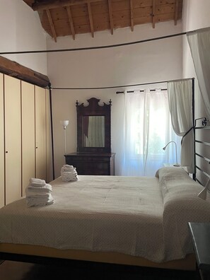 A bedroom with a bed, a dresser, a mirror, and a window with curtains.