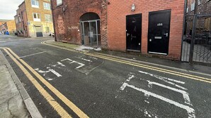 A street with a building featuring a no parking sign, a broken window, and a bicycle lane. - Modern 2 Bed Flat - Ideal for Families  (Ashton-under-Lyne)