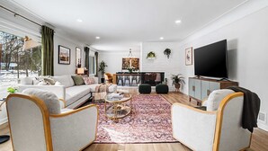 Un salon moderne comprenant un canapé, deux fauteuils, une table basse et un téléviseur.