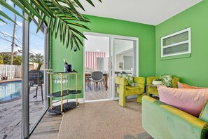 Ein Zimmer mit grüner Wand, einem Pool, einem Essbereich und einer Couch.