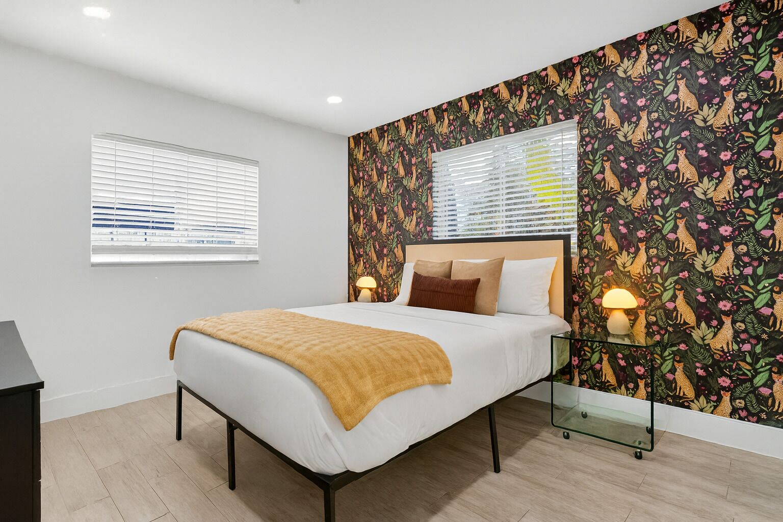 A modern bedroom with a bed, bedside lamps, a window, and a patterned wallpaper.