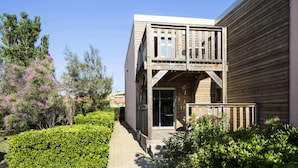 Un bâtiment moderne doté d’une terrasse en bois et d’une entrée avec une porte en verre.