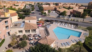 Un complexe hôtelier doté d’une piscine, de chaises longues et offrant une vue sur la plage.