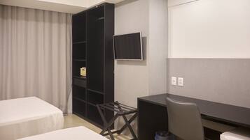 A hotel room with two beds, a desk, a chair, a TV, and a wardrobe.