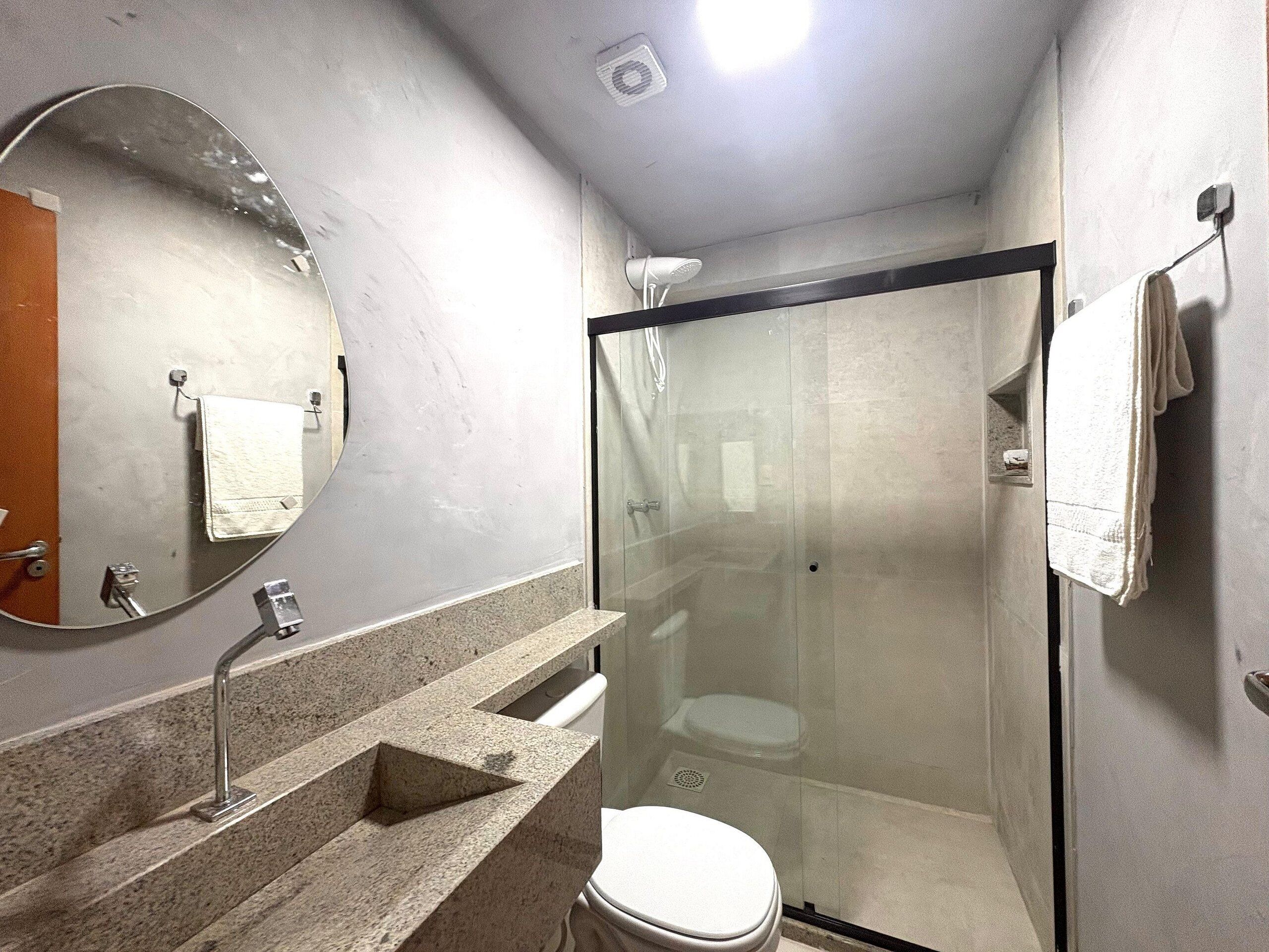 A bathroom with a glass-enclosed shower, a sink with a mirror, and a toilet.