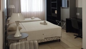 Una habitación de hotel con cama, escritorio, silla, lámpara y televisor.