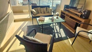 Un balcon avec un canapé, une table basse et un téléviseur.
