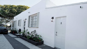 A white building with a door marked 'B', windows, and a security camera. - Modern Boho Studio Near Miami River (Miami)