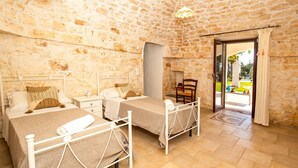 Una habitación con dos camas, paredes de piedra, una chimenea y vistas al exterior.