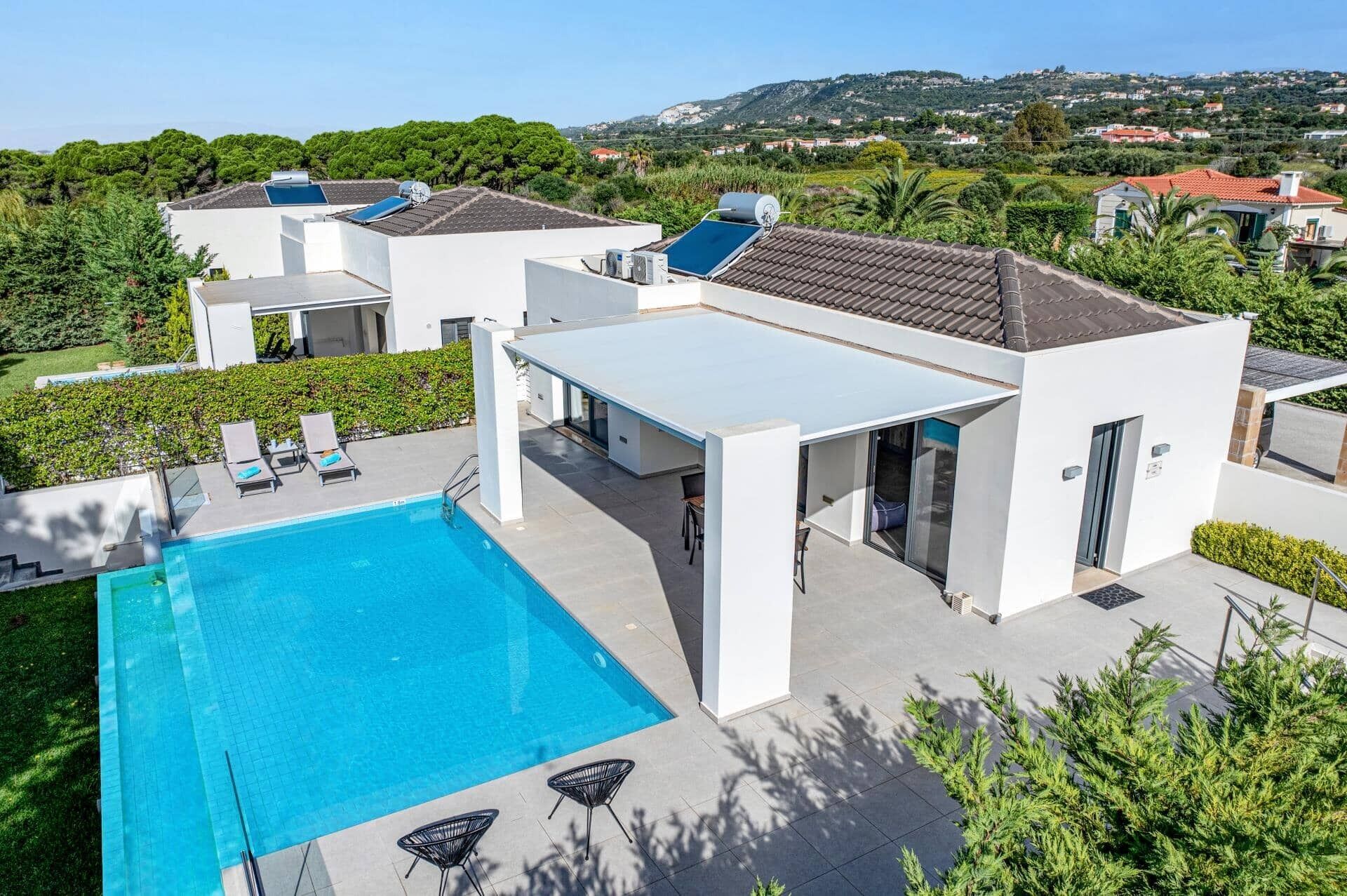 Uma villa moderna com piscina, área de estar ao ar livre e vista para a paisagem circundante.