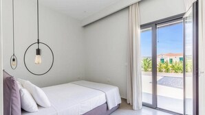 Ein modernes Schlafzimmer mit Bett, Ausblick nach draußen und einer Schiebetür.