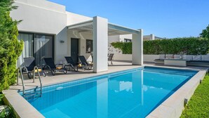 Ein moderner Poolbereich im Freien mit Liegestühlen und einer Pergola.