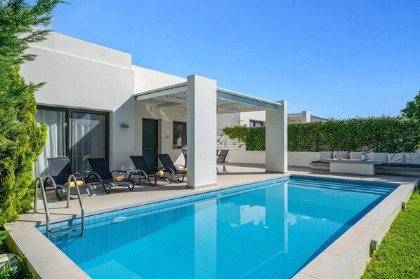 A modern outdoor pool area with lounge chairs and a pergola.