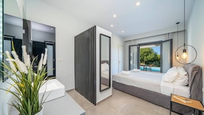 Une chambre moderne avec un lit, une table de chevet, un miroir et une vue sur une piscine.