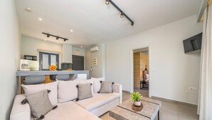 Un salon moderne avec un canapé, une table basse et un coin cuisine visible au fond.
