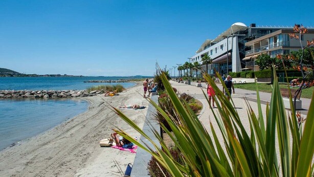 Un hotel frente a la playa con una playa arenosa, una zona de piscina y vistas al mar.