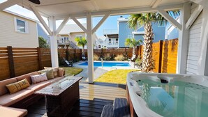 A covered patio with a hot tub, a wooden deck, a pool, and a view of neighboring houses. - "The Palm House": A pool, hot tub & ICWW views! (Carolina Beach)