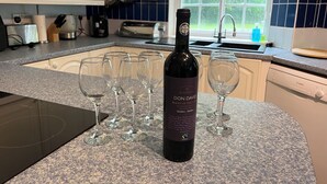 Une cuisine avec une bouteille de vin, des verres et un grille-pain.