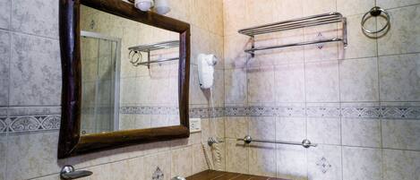 Un baño con tocador de madera, lavamanos, espejo, toallero y secador de pelo.