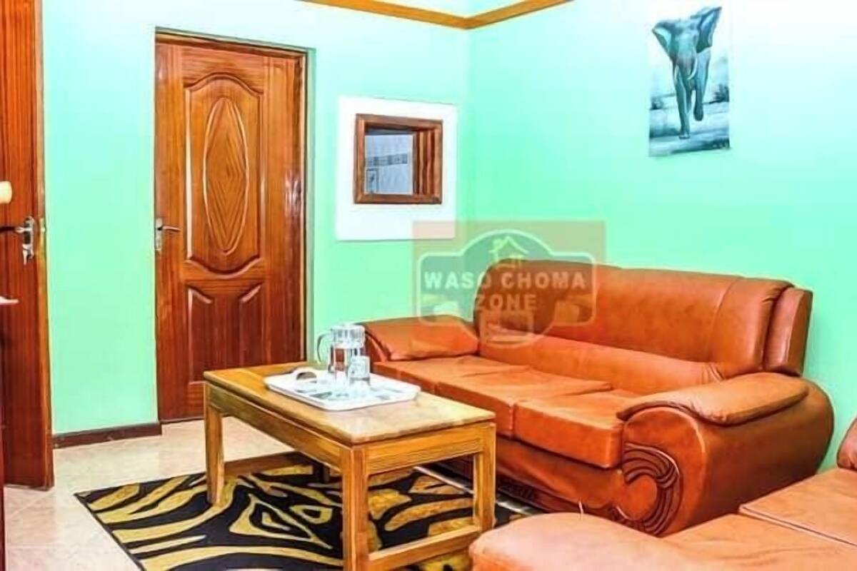 A living room with a brown leather sofa, a wooden coffee table, and a patterned rug.