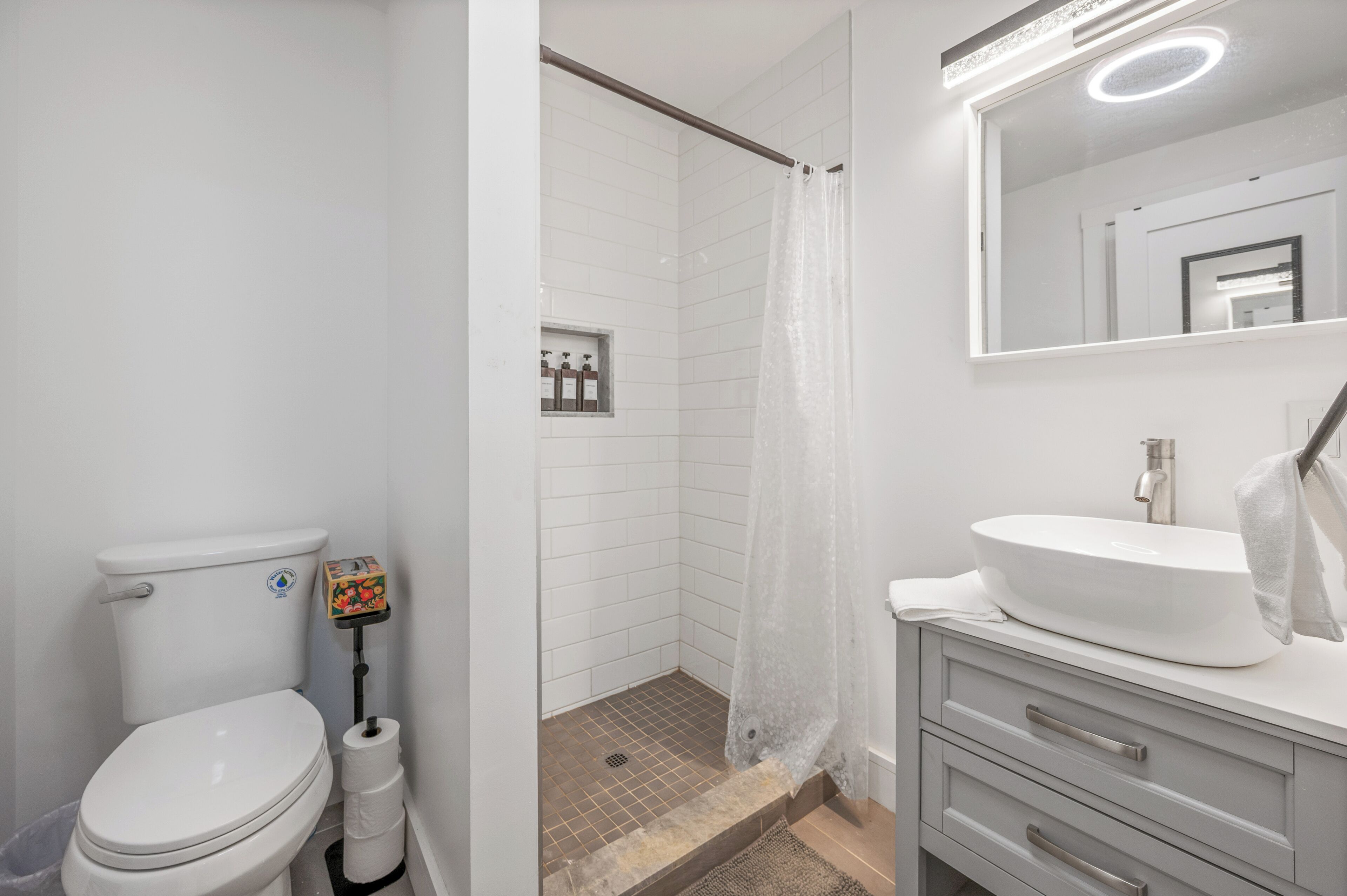 A modern bathroom with a toilet, shower, and sink.