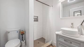 A modern bathroom with a toilet, shower, and sink.