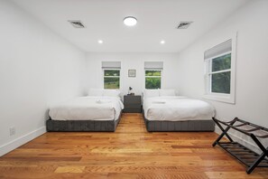 A bedroom with two beds, a nightstand, and a window with blinds. - Spacious 8 BR Family Winter Escape + Hot Tub - 25 minutes to ski and tubing!! (Ellenville)