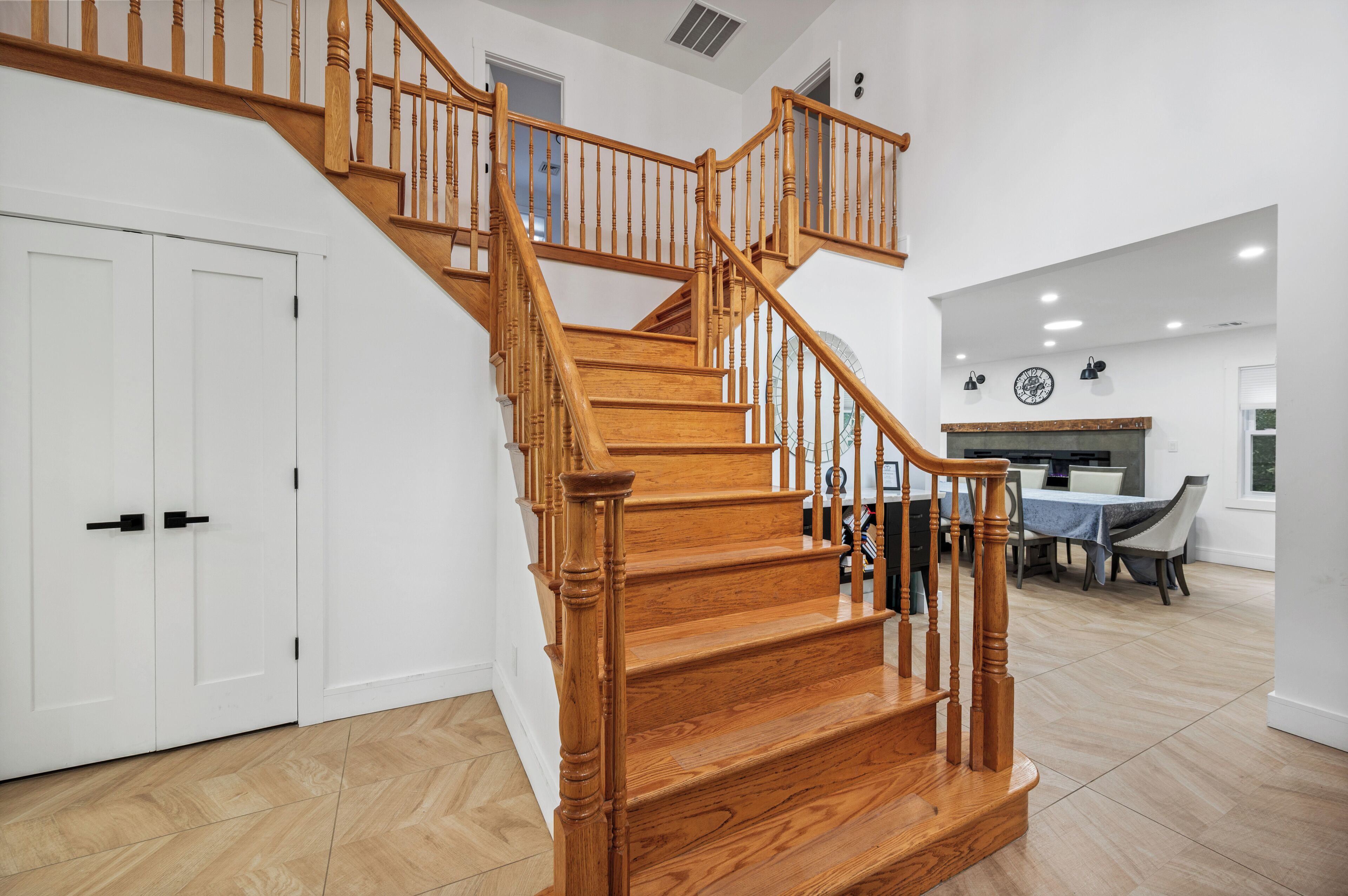 Eine Holztreppe mit Geländer, weiße Türen und ein Essbereich mit Tisch und Stühlen.
