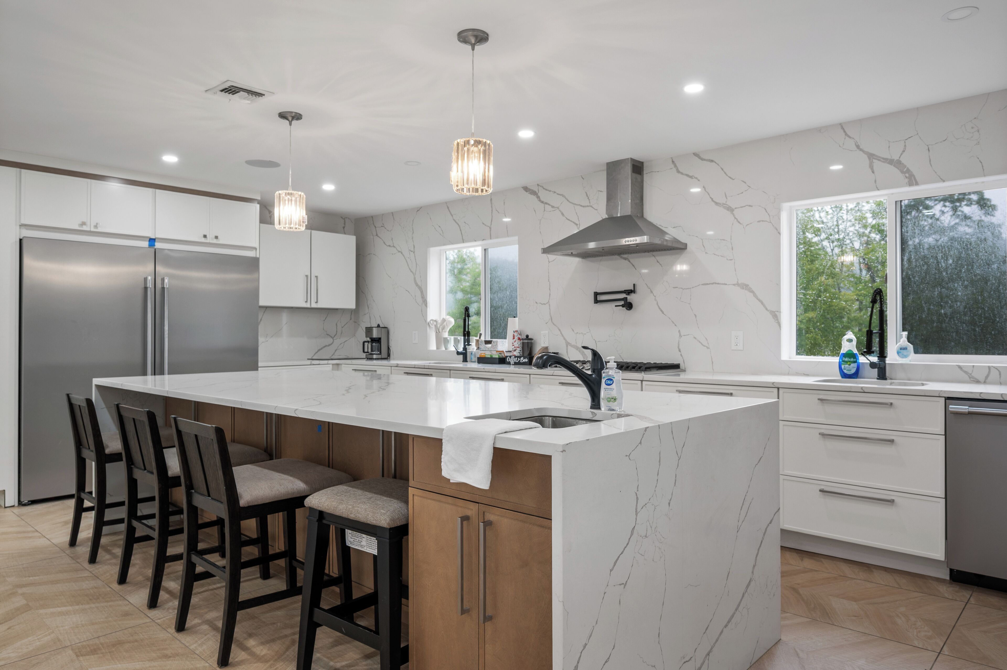 A modern kitchen with a large island, stainless steel appliances, and a view of the outdoors.