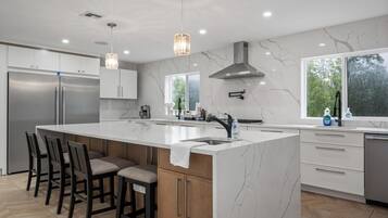 A modern kitchen with a large island, stainless steel appliances, and a view of the outdoors.