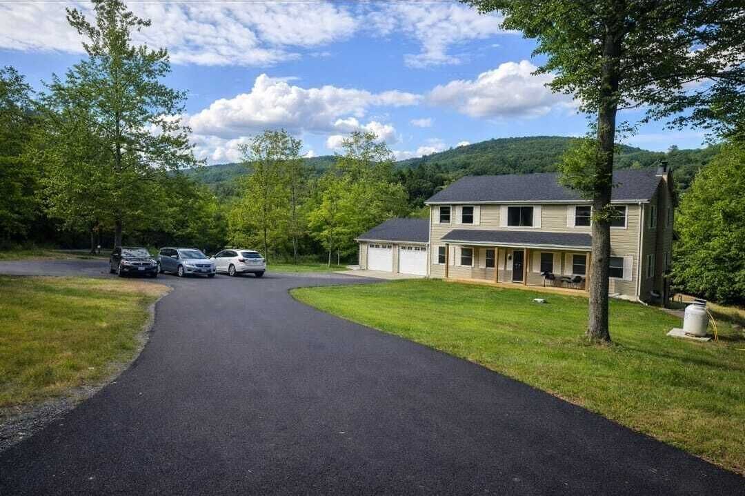 A two-story house with a driveway leading to a parking area.