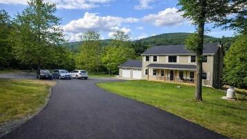 A two-story house with a driveway leading to a parking area.