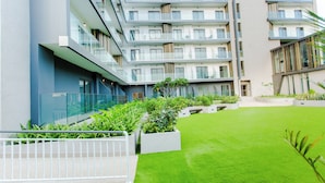 A modern multi-story building with balconies, a courtyard with artificial grass, and planters. - Modern Executive Studio Apartment at Lennox (Accra)