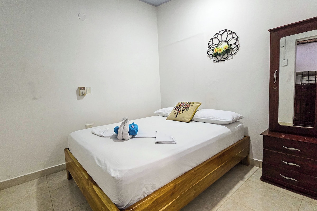 Una cama individual con estructura de madera, una mesita de noche, un espejo y un adorno en la pared.