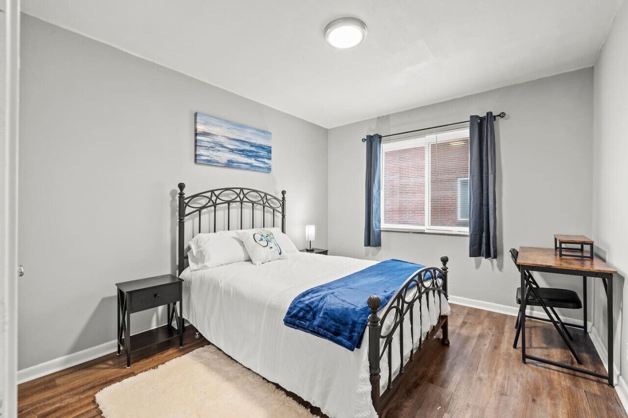 Un dormitorio con cama, mesita de noche y escritorio con silla.