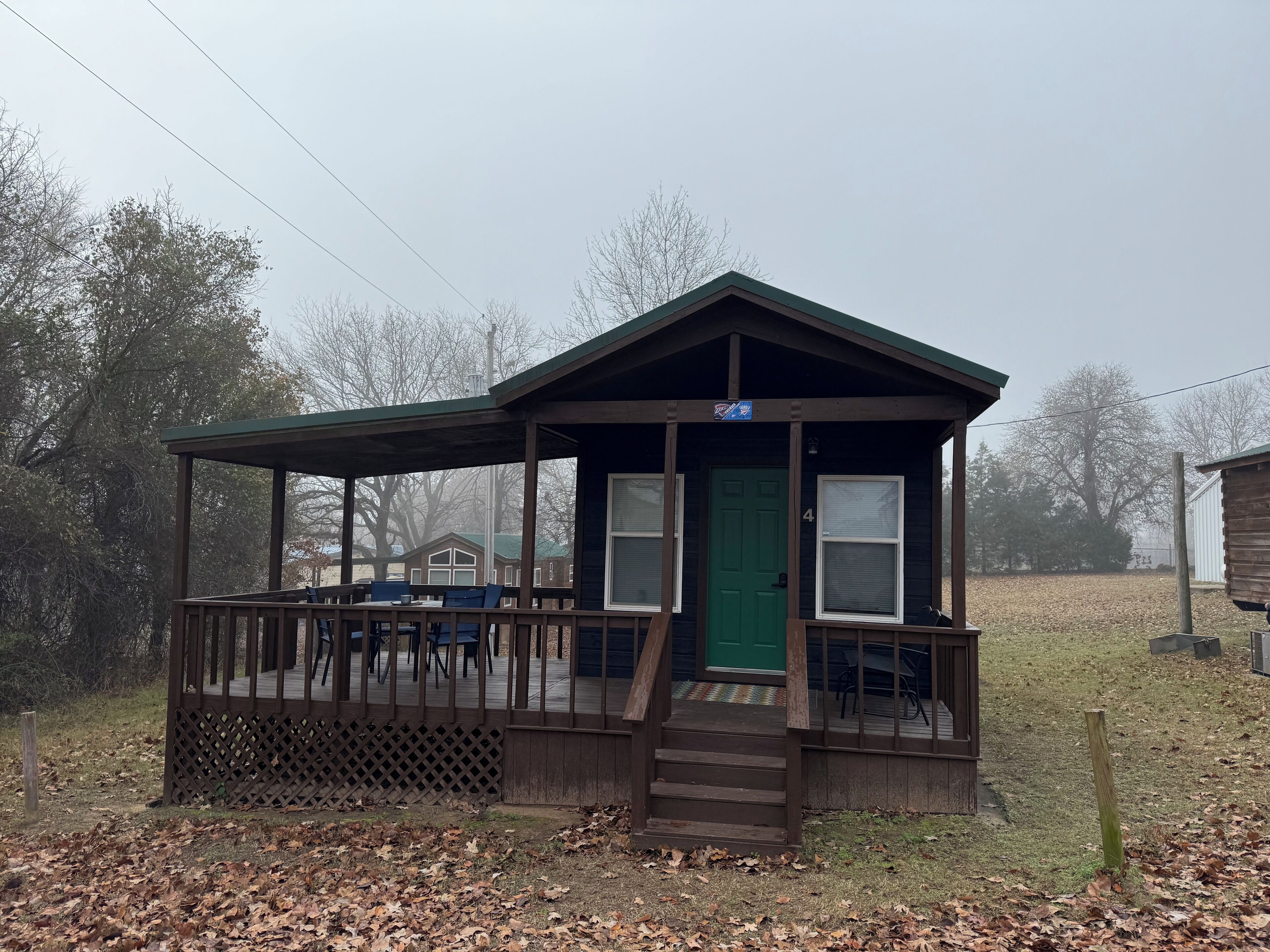 A small cabin with a porch, a green door, and a sign above the door.