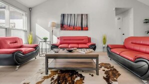 Un salon avec deux canapés en cuir rouge, une table basse en bois et un tapis en peau de vache.