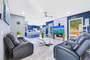 A modern living room with a sofa, a TV, and a fireplace. - Luxe Modern Spacious Pool PingPong EV Sleeps 20! (Frisco)