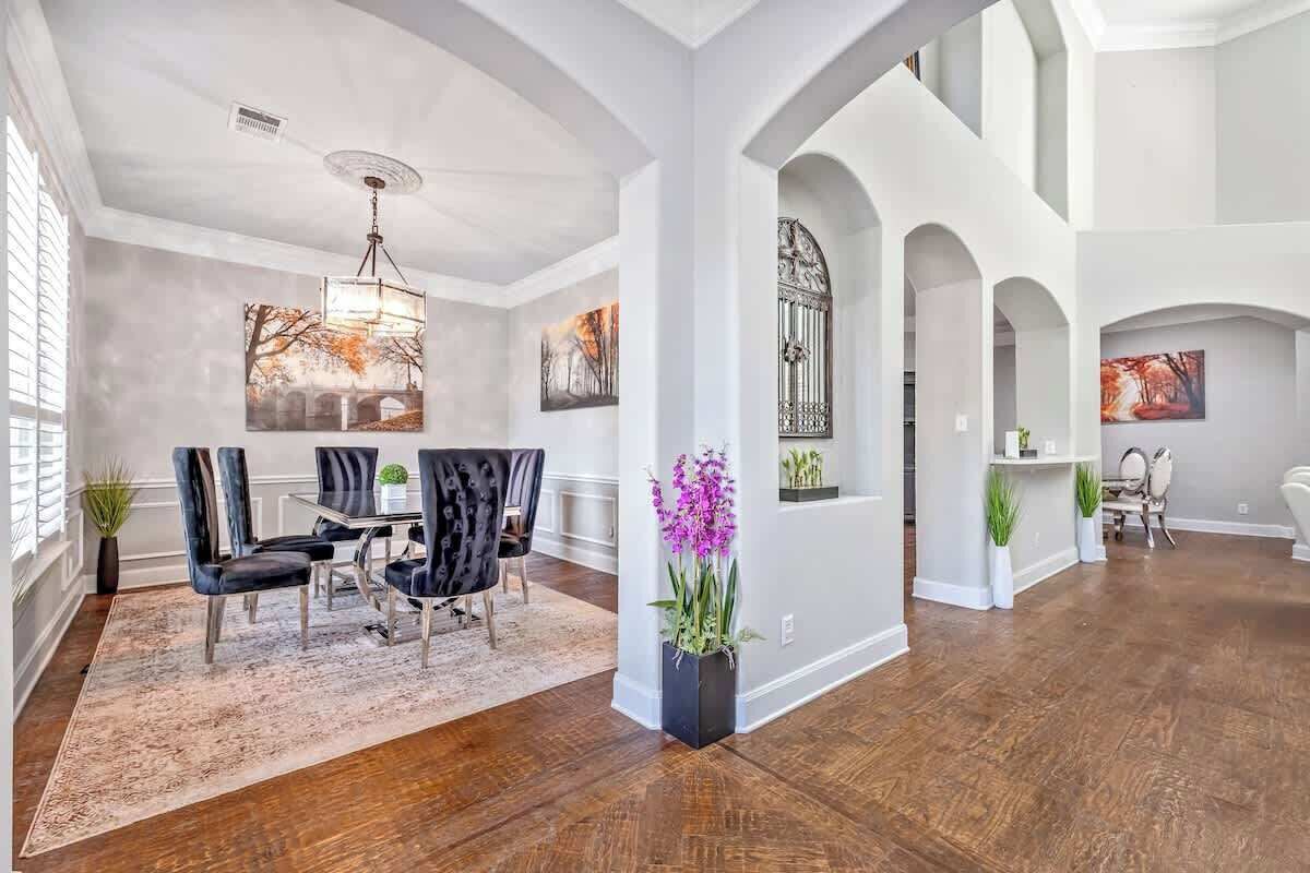 A spacious interior with a dining area, wooden flooring, and decorative elements like plants and artwork.