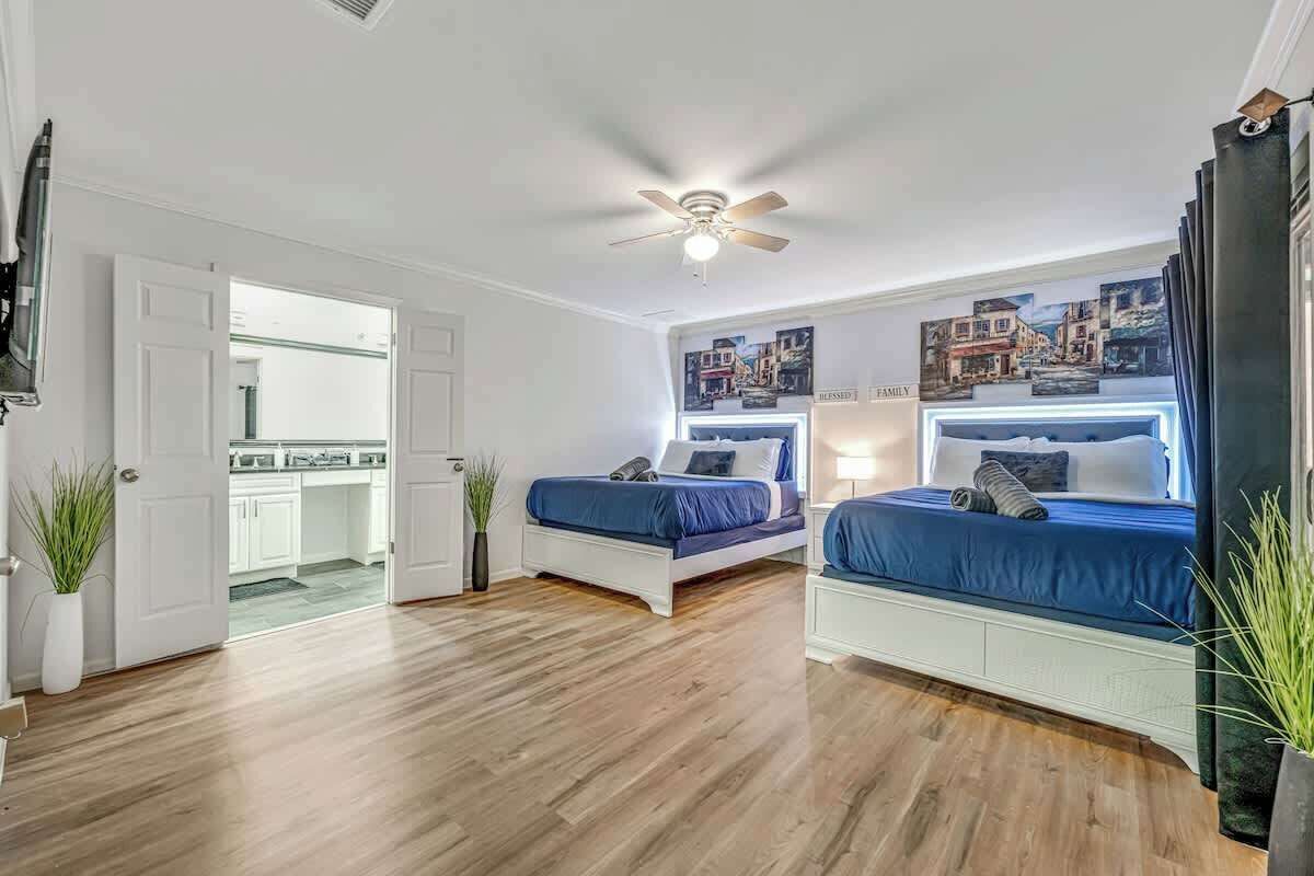 Une chambre avec deux lits, un ventilateur de plafond et une vue sur la cuisine.