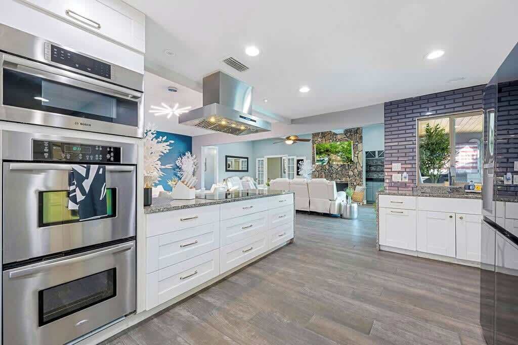 Cocina moderna con electrodomésticos integrados, una isla grande y un comedor con vistas.
