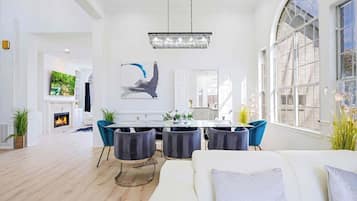 Ein geräumiges Wohnzimmer mit Kamin, einem Essbereich mit einer Chandelier und großen Fenstern.