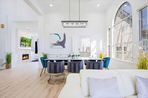 Ein geräumiges Wohnzimmer mit Kamin, einem Essbereich mit einer Chandelier und großen Fenstern.
