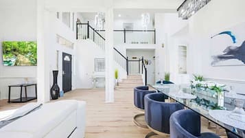 Ein modernes Interieur mit einer Treppe, einem Essbereich mit runden Tischen und einem großen Kunstwerk an der Wand.