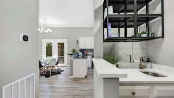 A modern kitchen with white cabinetry, a built-in shelf, and a large window.