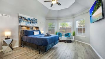 A bedroom with a bed, a ceiling fan, a TV, and a window with blinds.