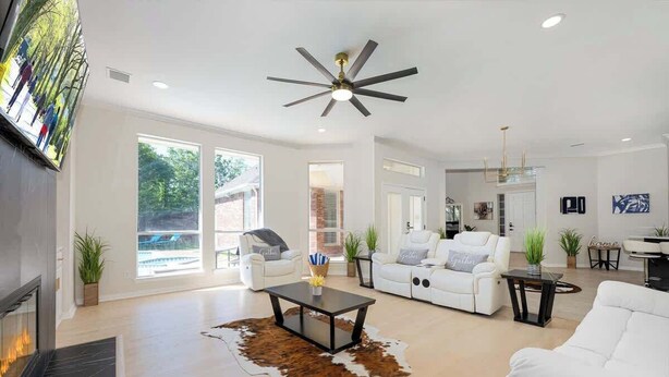 A spacious living room with a fireplace, a ceiling fan, and a cowhide rug. - Exquisite 6 BR Retreat PoolSpa 4.5 Bath Sleeps 20+ (Richardson)