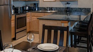 Una cocina con armarios de madera, un refrigerador de acero inoxidable, un microondas, una estufa, un fregadero y una mesa de comedor con sillas.