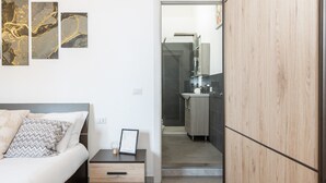 A modern bedroom with a bed, bedside table, and artwork on the wall. - Costa Ovest Apartments (Nurachi)